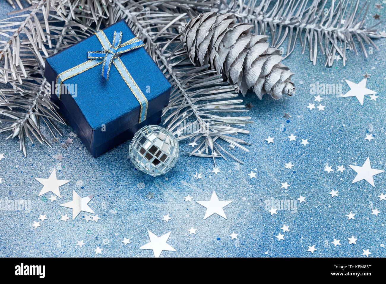 silver christmas tree branches with cones, decorations and blue gift ...