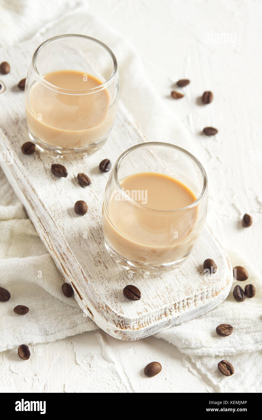 Irish cream coffee liqueur and coffee beans over white wooden