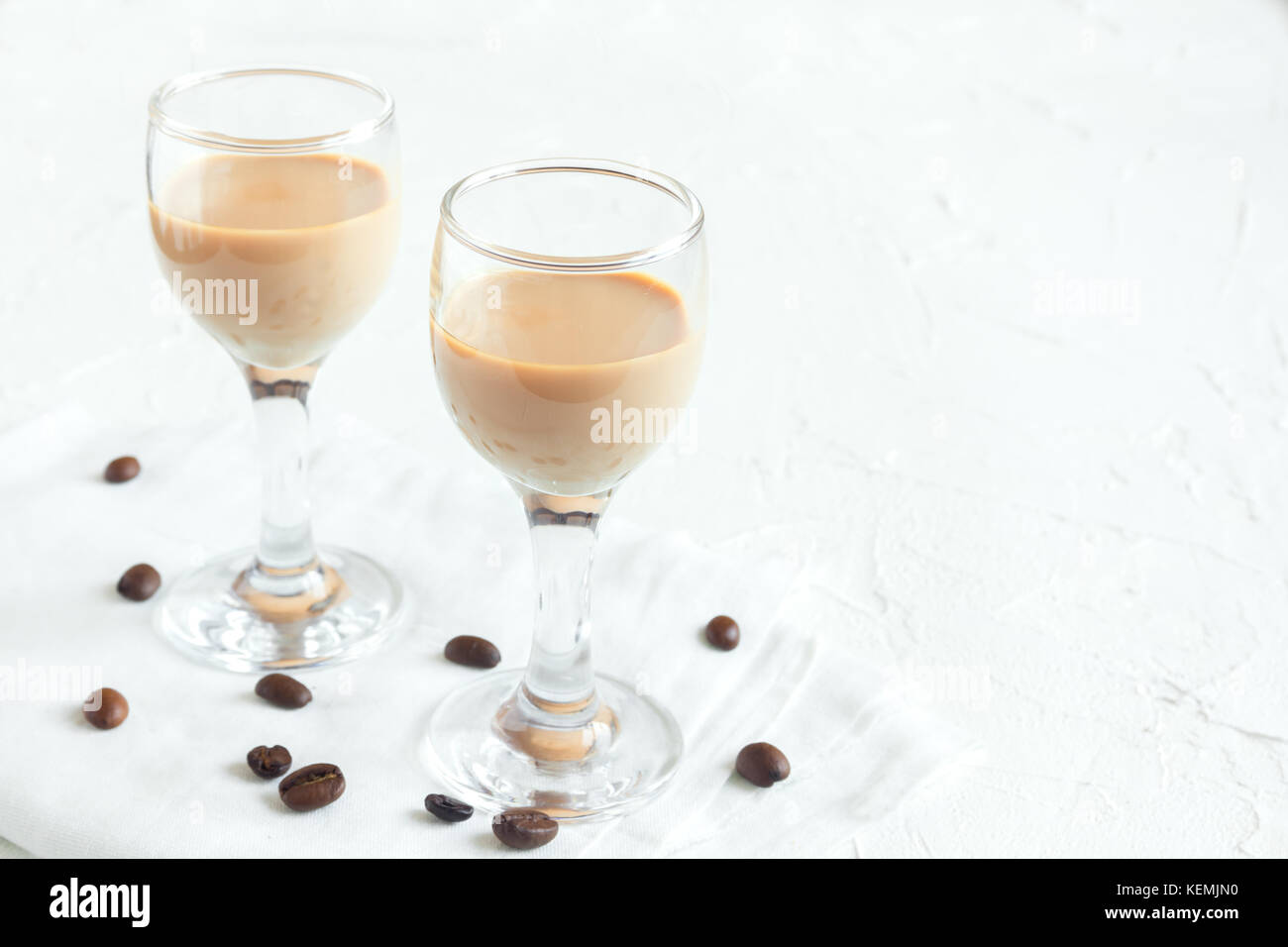 Irish cream coffee liqueur and coffee beans over white wooden