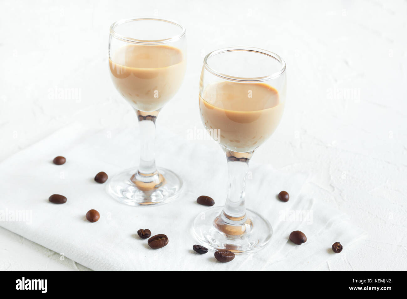 Irish cream coffee liqueur and coffee beans over white wooden