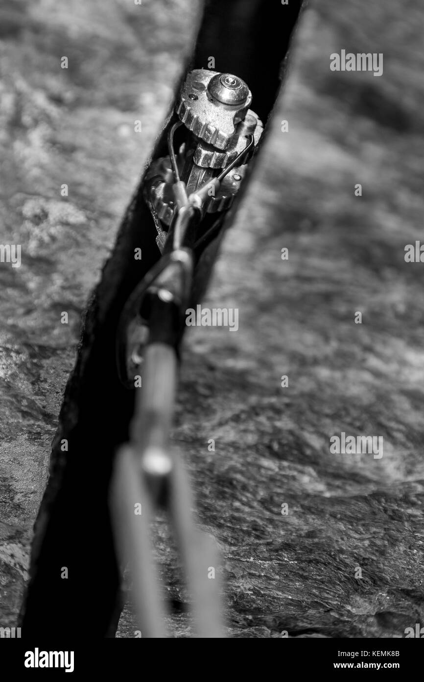 Closeup ropes, cam and carabiners in rock for mountain climbing Stock