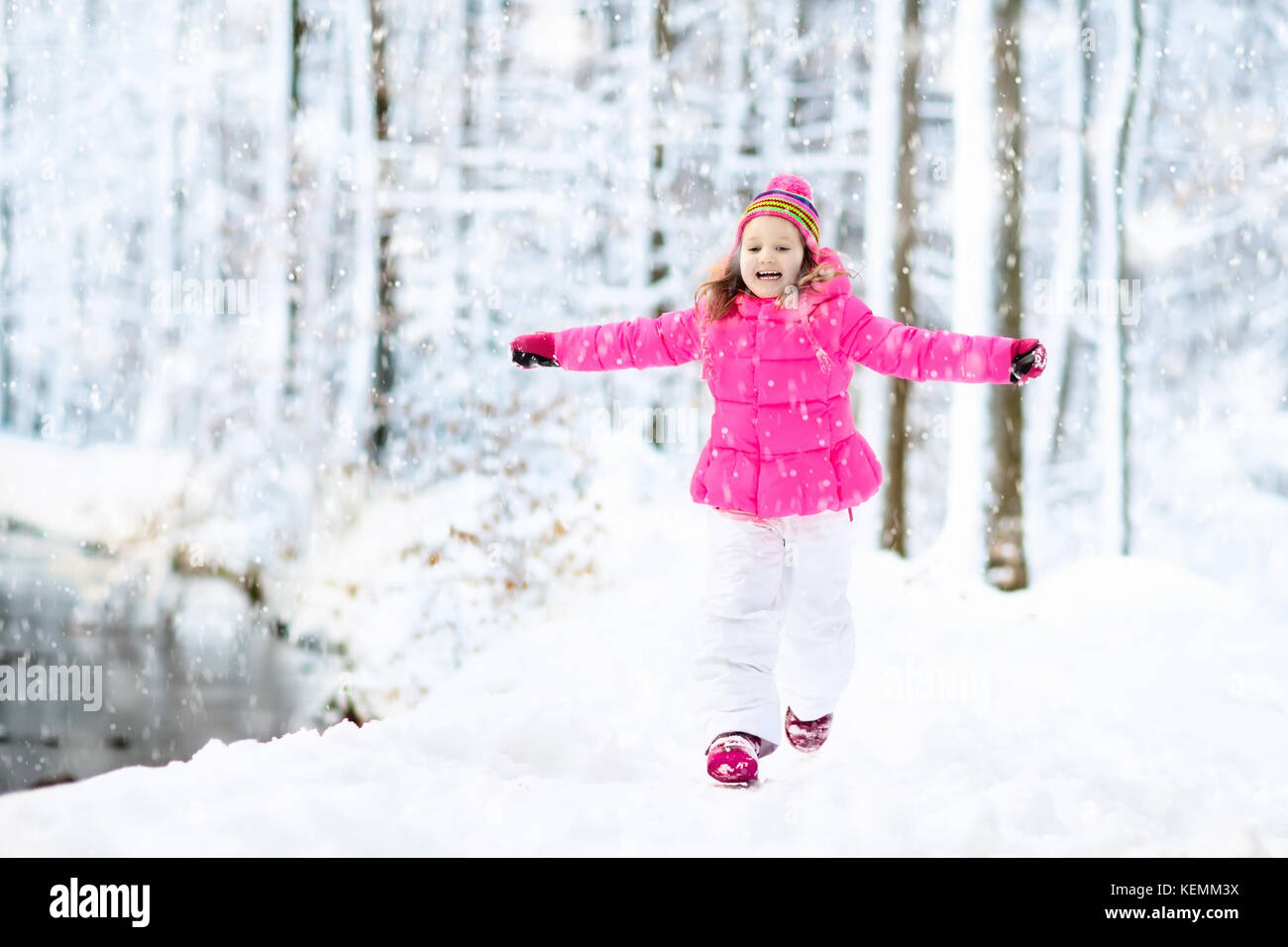 Child playing with snow in winter. Little girl in colorful jacket and ...
