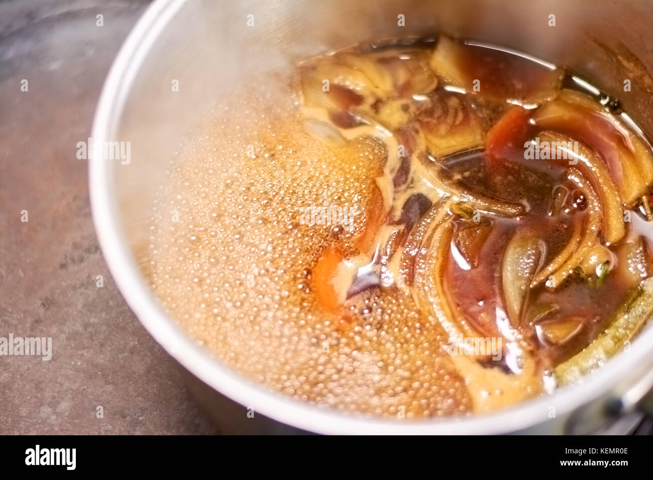 Flavor shank of lamb boiling in saucepan. Slow cooked leg of lamb with broth in casserole close