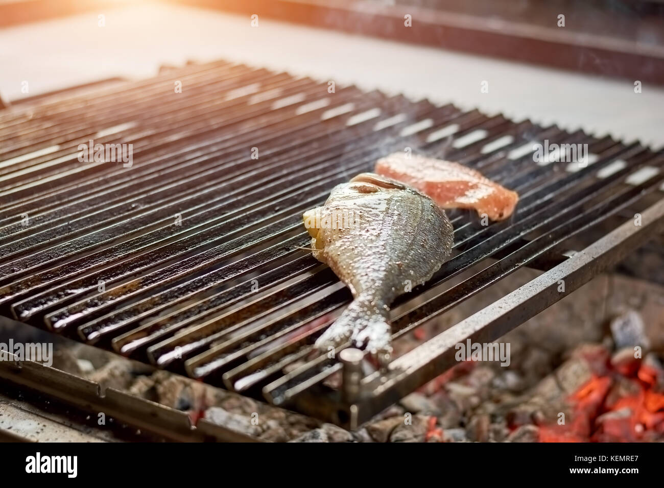 Dorado fish grilling on barbecue grill. Raw fish with spices and lemon on the grill close up. Stock Photo