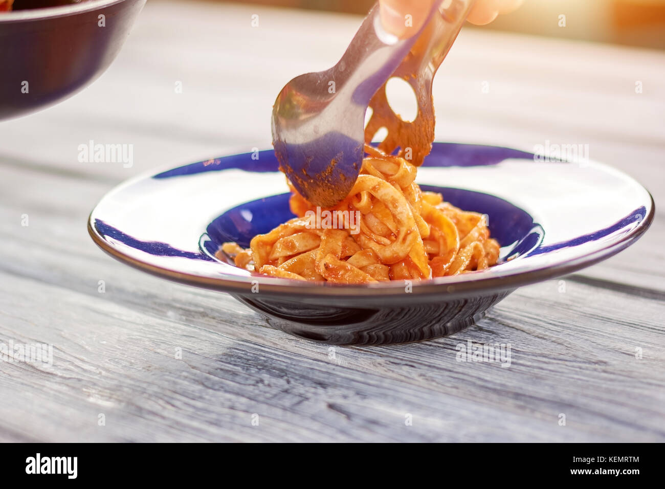 Kitchen stainless tongs putting pasta on plate. Appetizing pasta frutti di maré. Culinary and