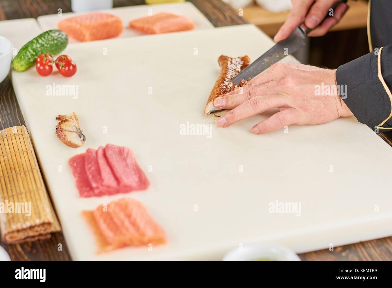 Chef hands with knife slicing smoked eel. Salmon, tuna and eel for
