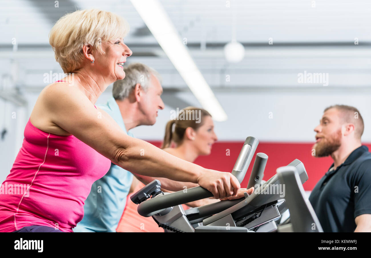 Personal trainer instructs senior woman about spinning at the gy Stock Photo