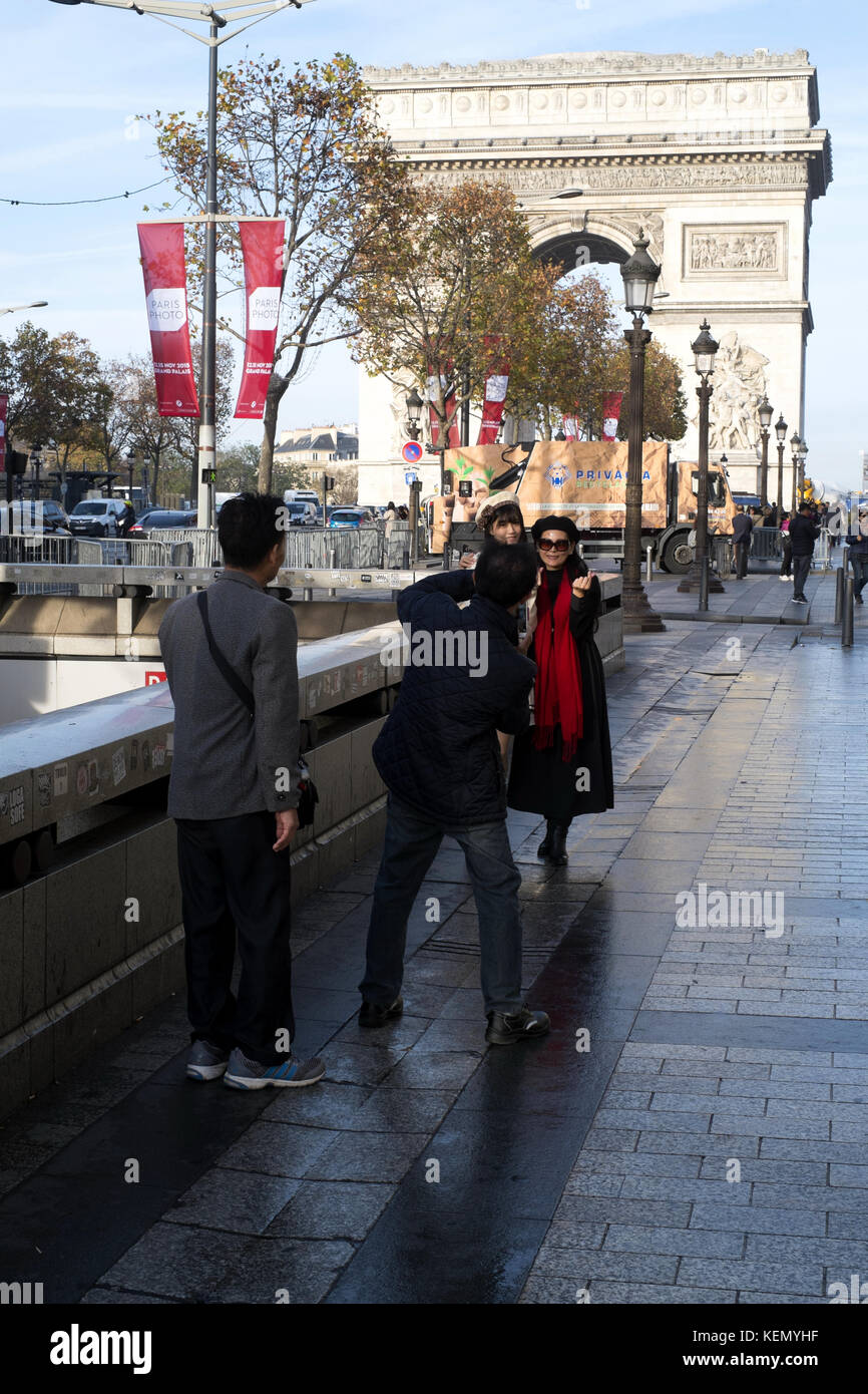Man taking photo of two ladies at Avenue des Champs Elysees close to Arch of Triumph, Arc de Triomphe, Paris Stock Photo