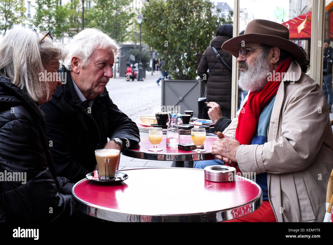 Two elderly men and a woman at a café in Paris Stock Photo