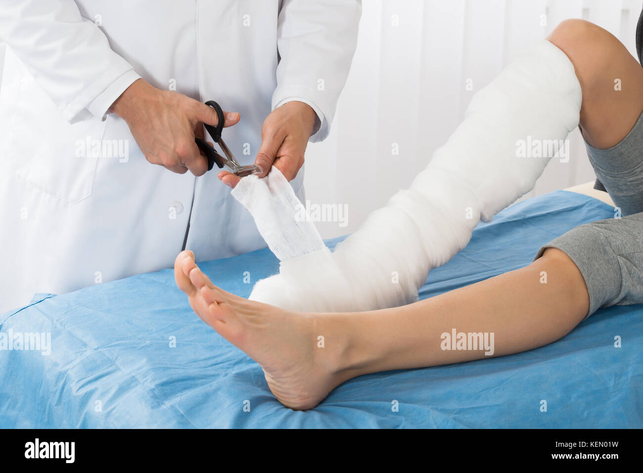 Doctor Bandaging Leg Of Patient In Hospital Stock Photo