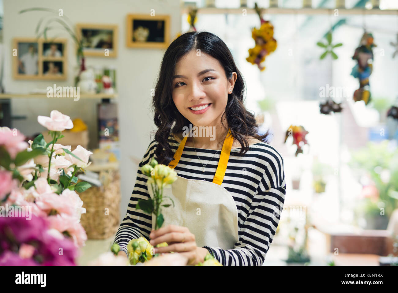 Young beautiful asian girl florist taking care of flowers at workplace ...