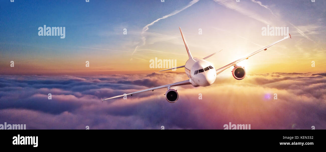 Commercial airplane flying above clouds in dramatic sunset light. High ...