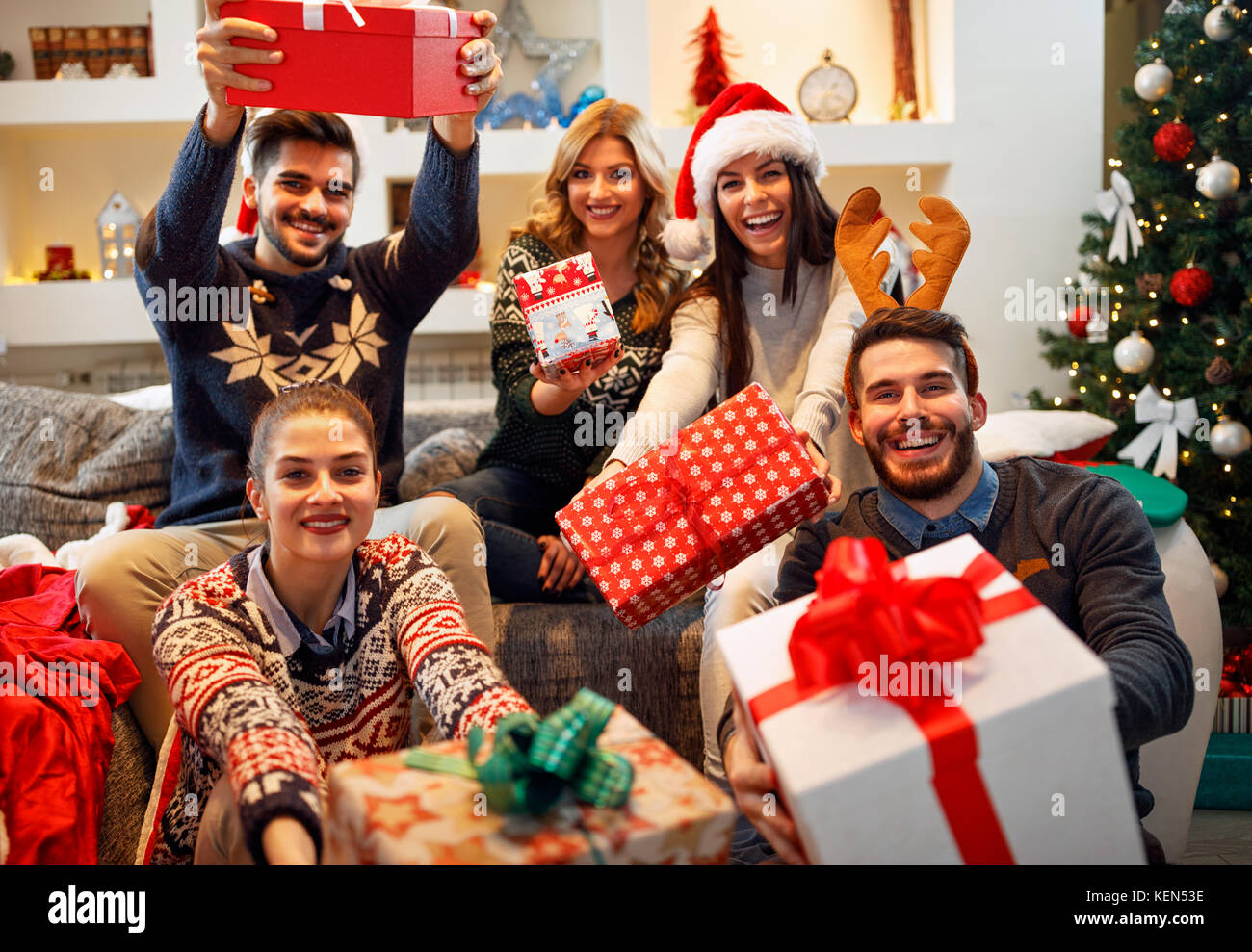 family, Christmas, holidays, happiness and people concept- happy friends sharing Christmas gifts Stock Photo
