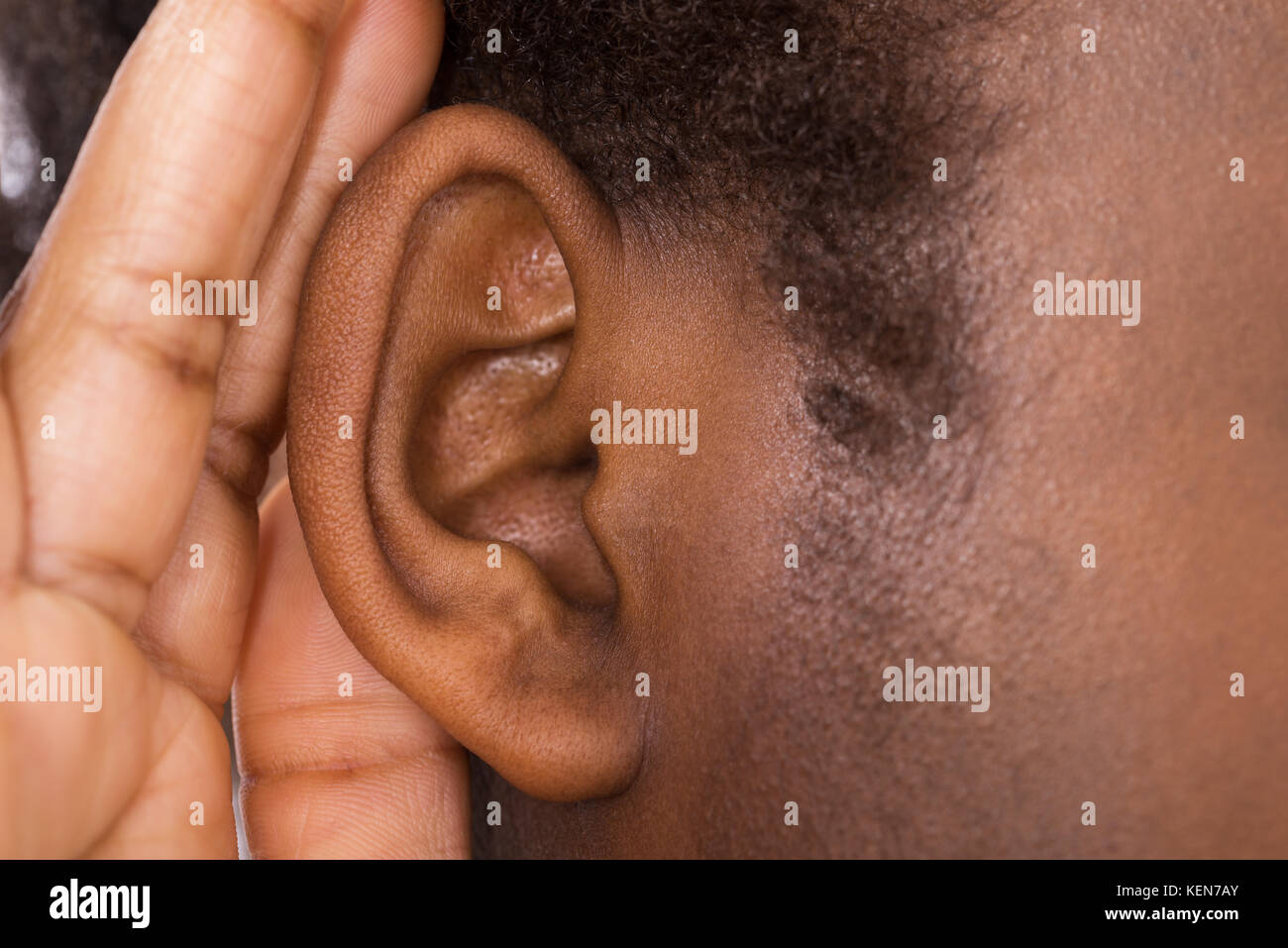 Close-up Of An African Woman Trying To Hear With Hand Over Ear Stock Photo