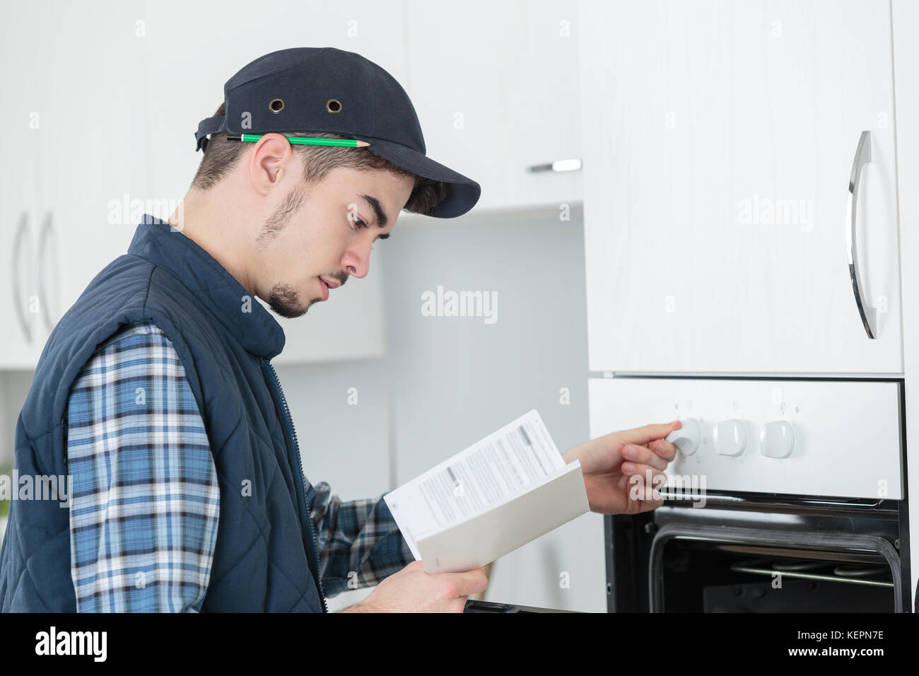 young repairman in overall installing brand new oven in kitchen Stock