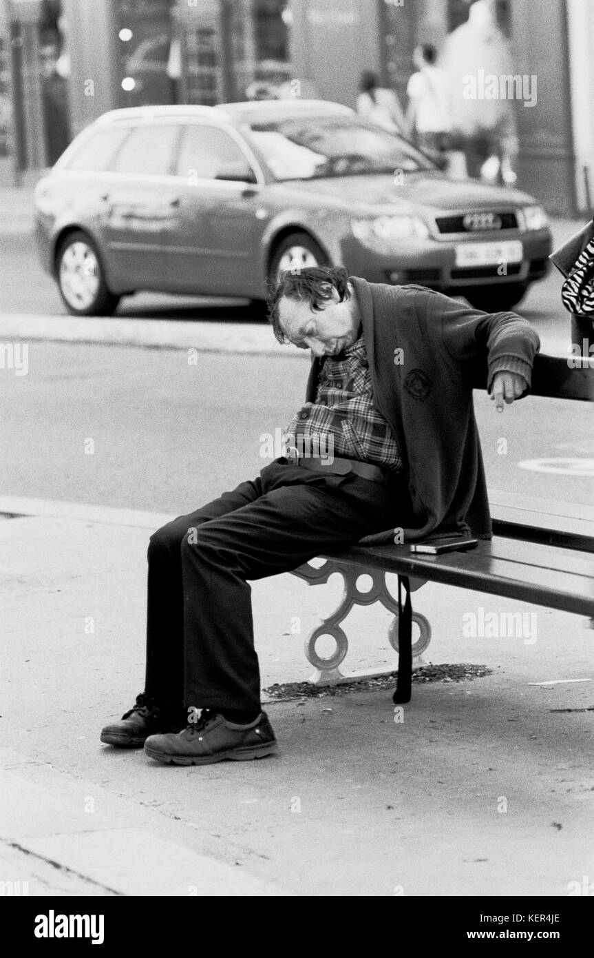 PARIS SOLITUDE - MAN SLEEPING ON A BENCH TAKING NO NOTICE OF THE ROAD TRAFFIC - PARIS HOMELESS - SILVER IMAGE © Frédéric BEAUMONT Stock Photo
