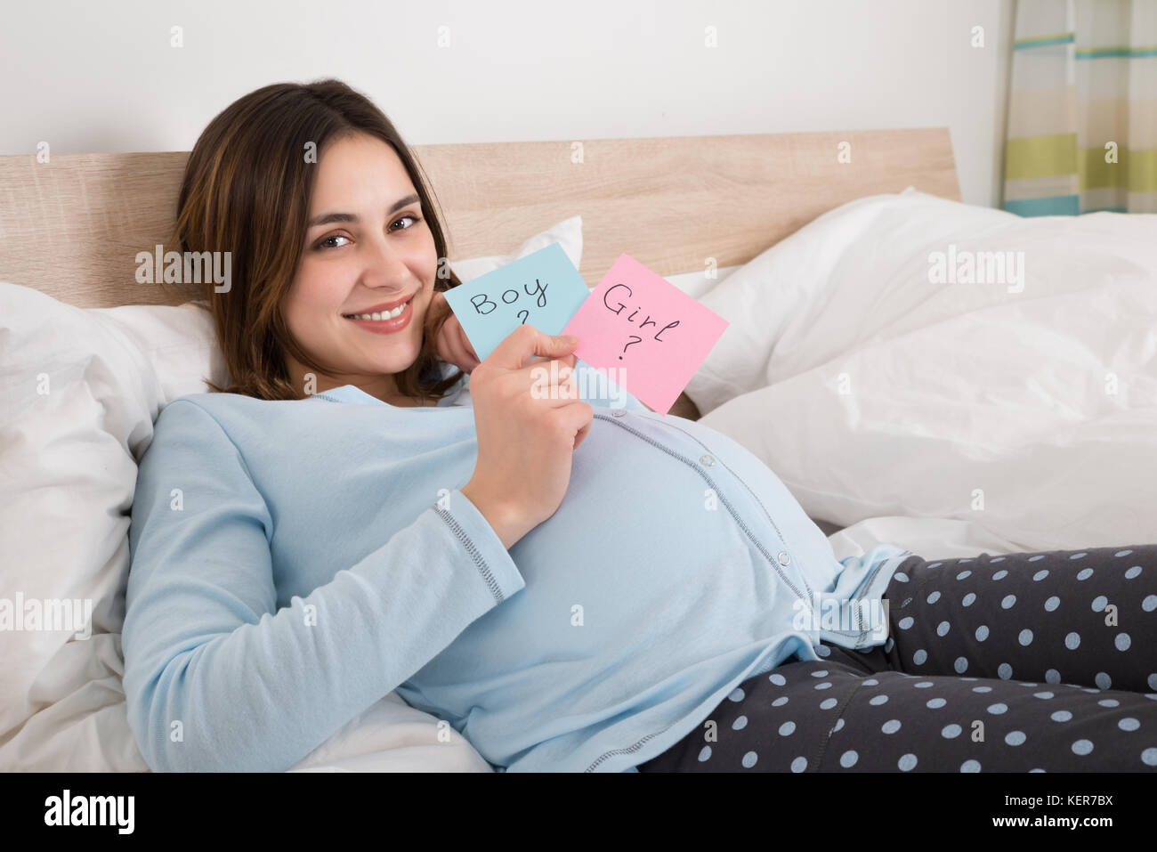 Happy Young Pregnant Woman Holding Paper With Girl And Boy Written On It Stock Photo