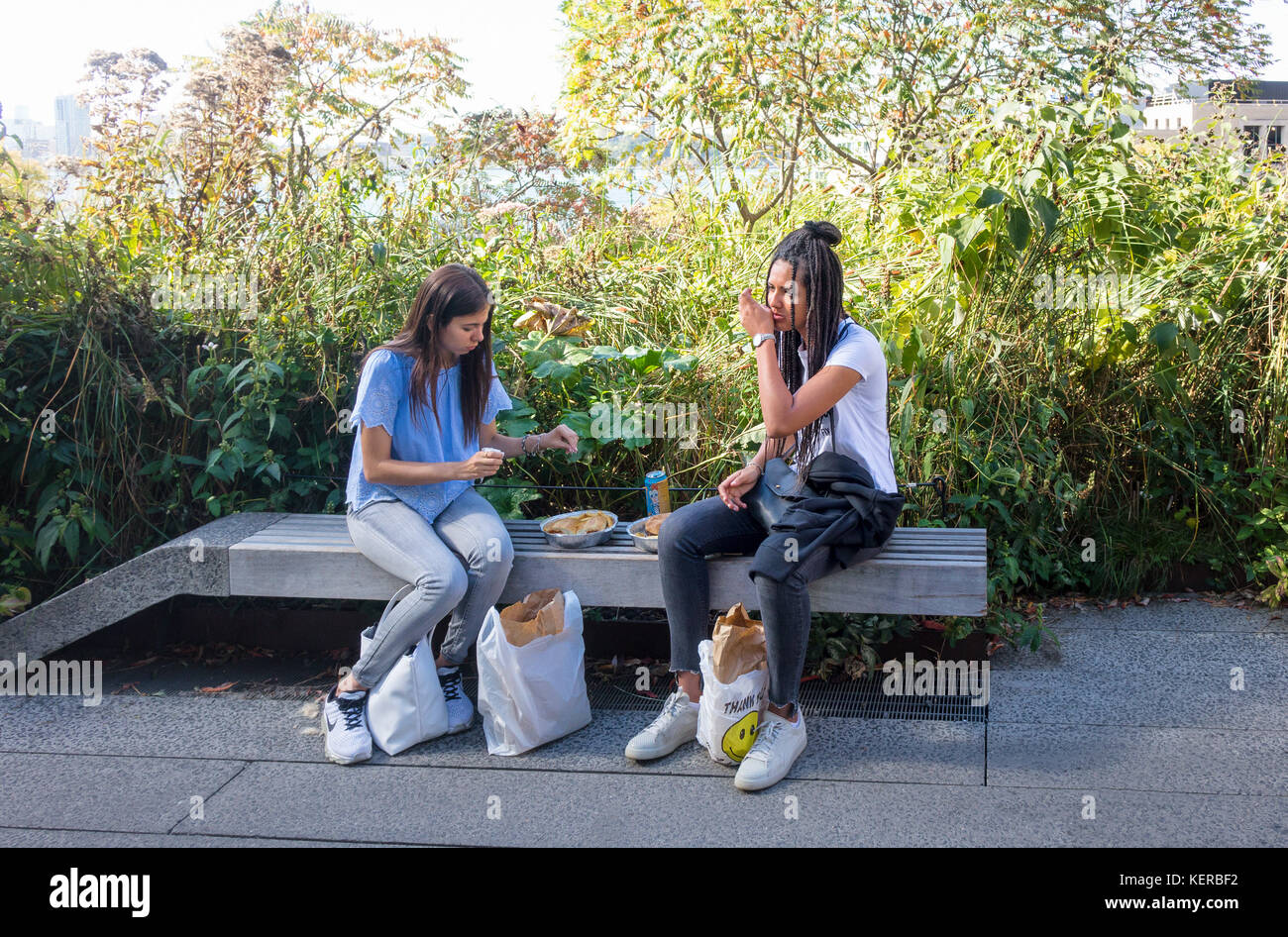Two young women eating a picnic lunch on the High Line in New York City Stock Photo