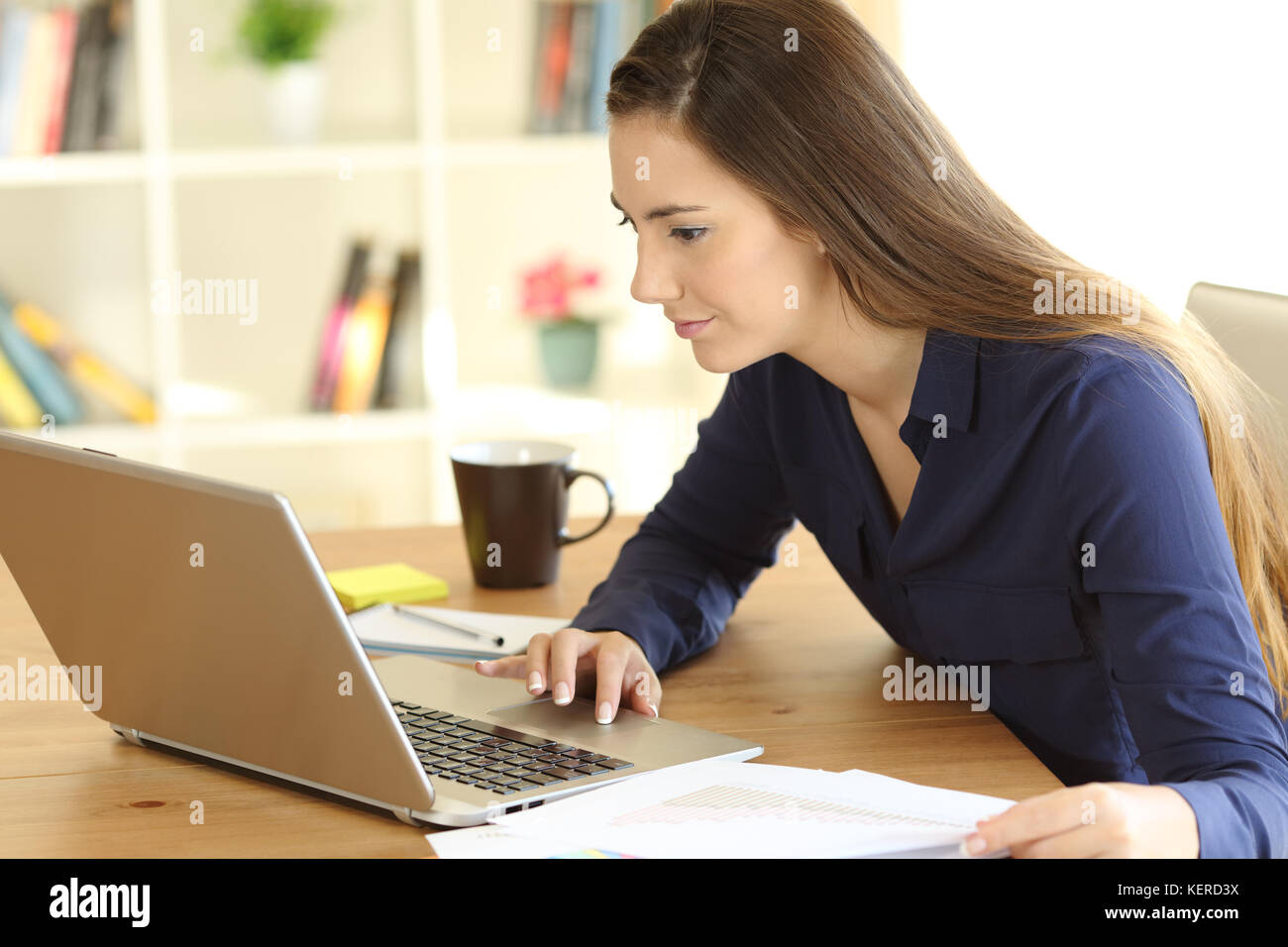 Serious freelance worker working on line with a laptop on a desk at home Stock Photo