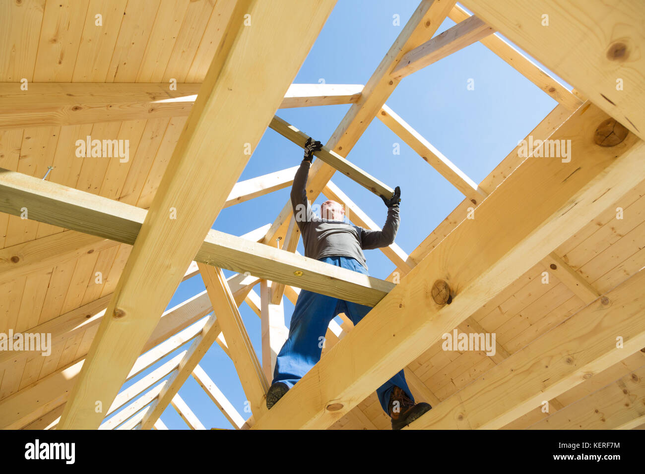 Builder at work with wooden roof construction. Stock Photo