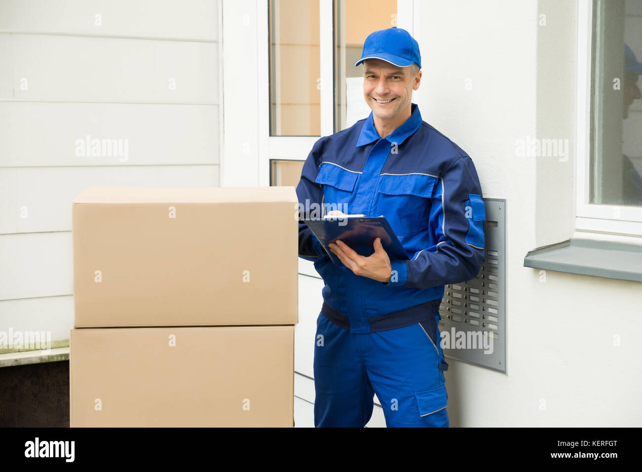 Delivery Man With Cardboard Boxes Writing On Clipboard Stock Photo Alamy