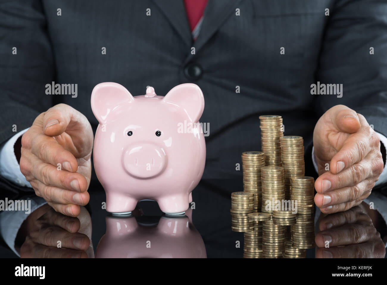 Close-up Of Businessman Hand Protecting Piggybank With Stack Of Coins Stock Photo