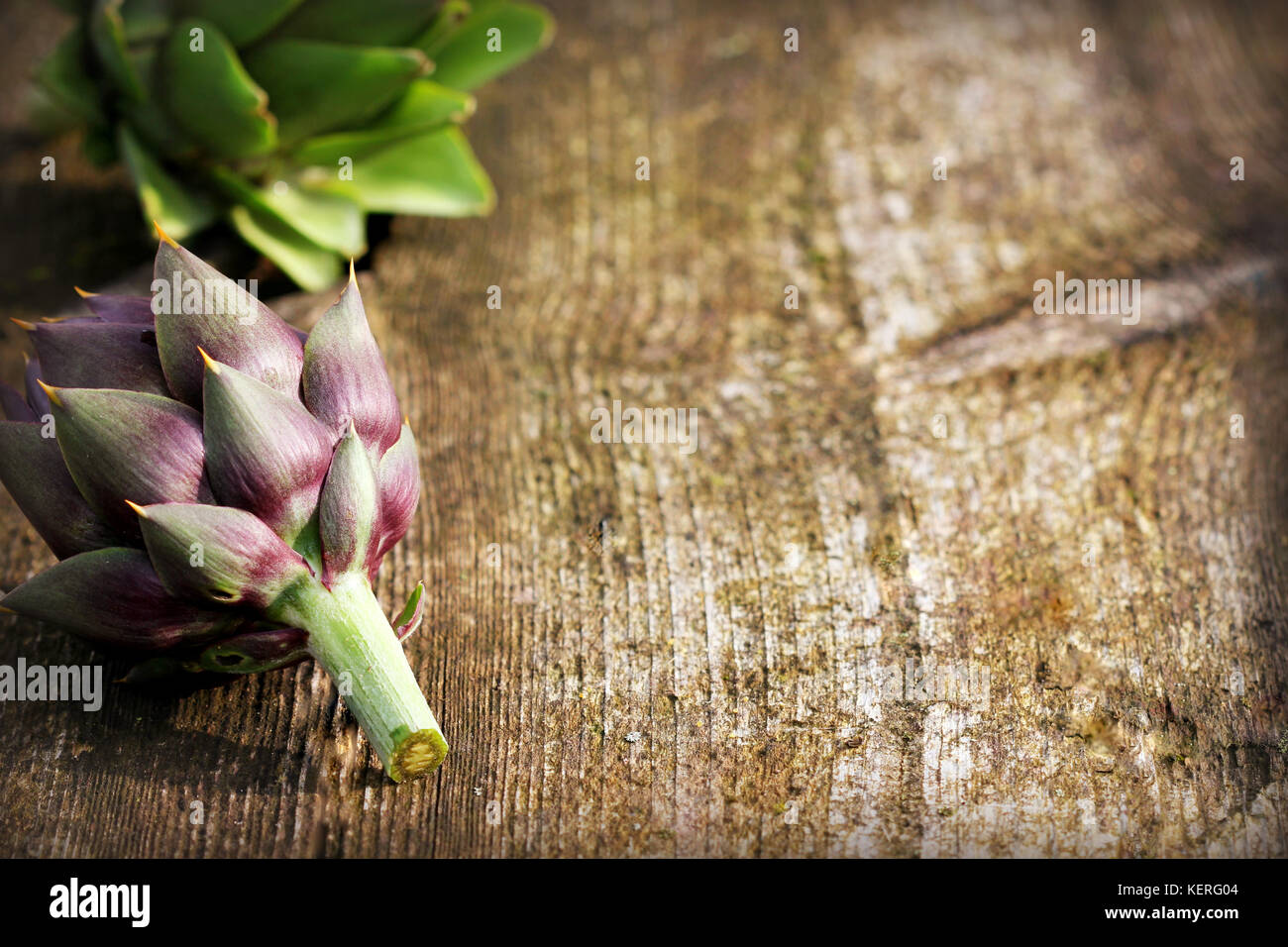 Green and purple artichokes on rustic wooden background Stock Photo Alamy