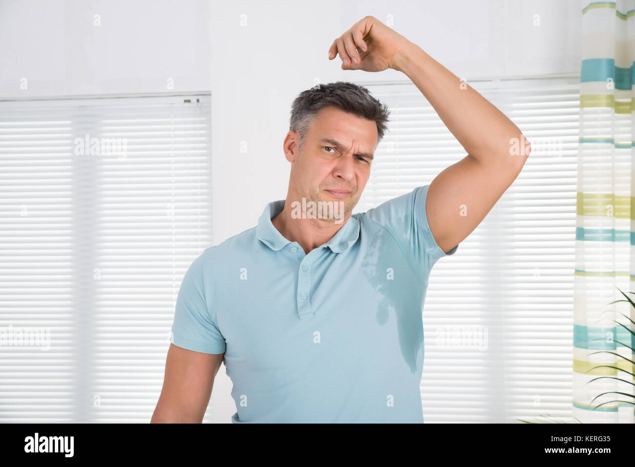 Man With Hyperhidrosis Sweating Very Badly Under Armpit At Home Stock Photo