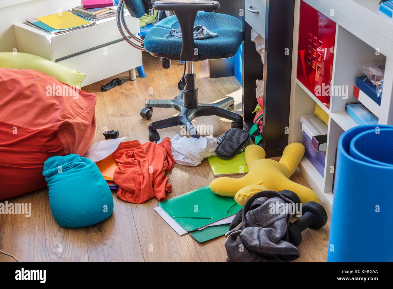 Boy messy bedroom with clothes and colorful pillows on the floor Stock Photo