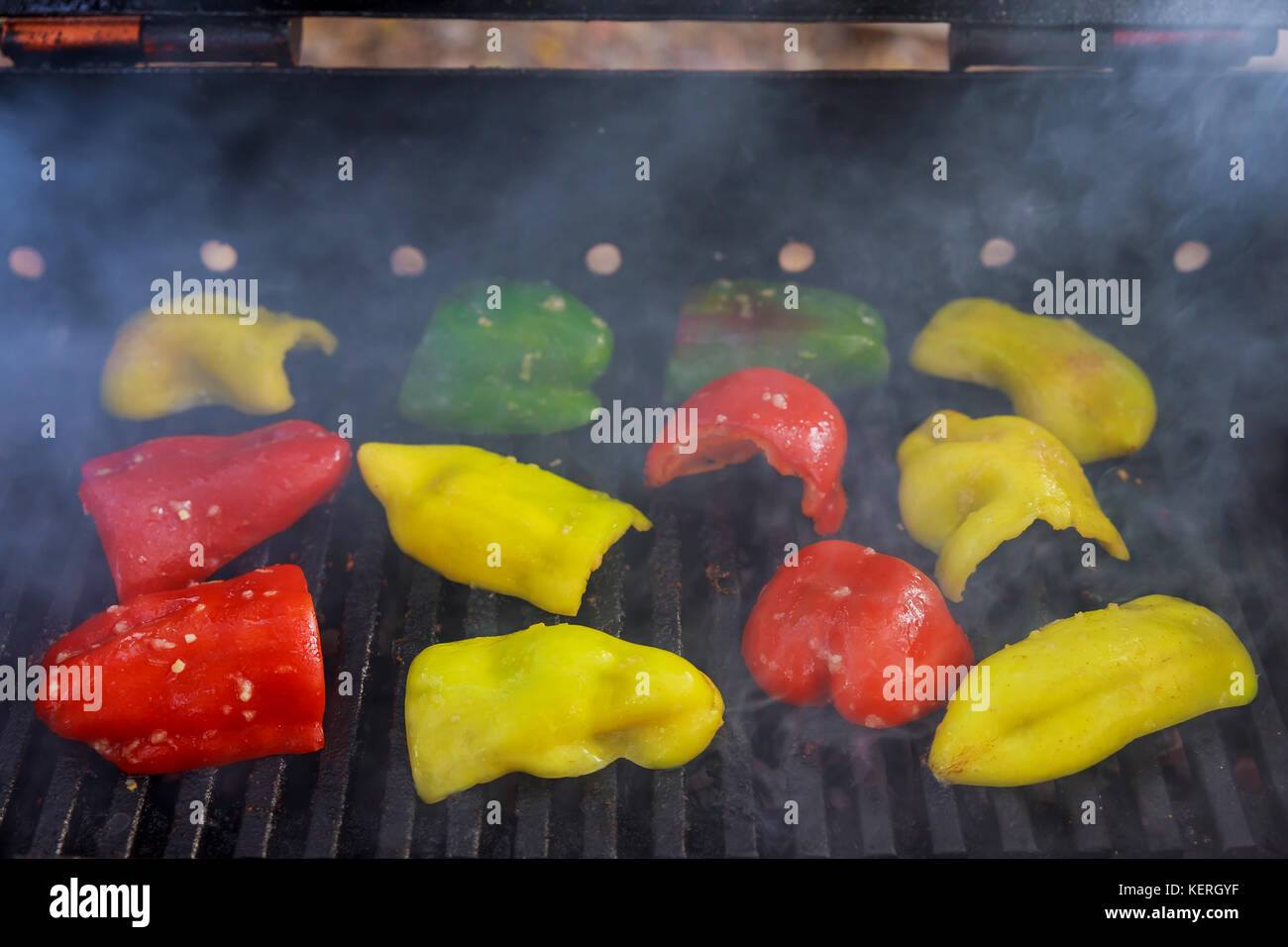 Various colors of bell peppers grilling on a charcoal BBQ Stock Photo