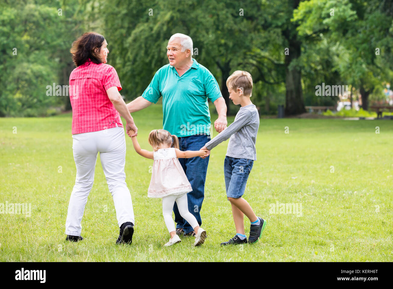 Happy Family Playing With Kids And Having Fun In Park Stock Photo - Alamy