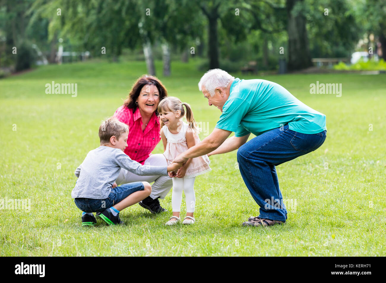 Happy Old Grandparents Having Fun With Grandchildren  In Park Stock Photo