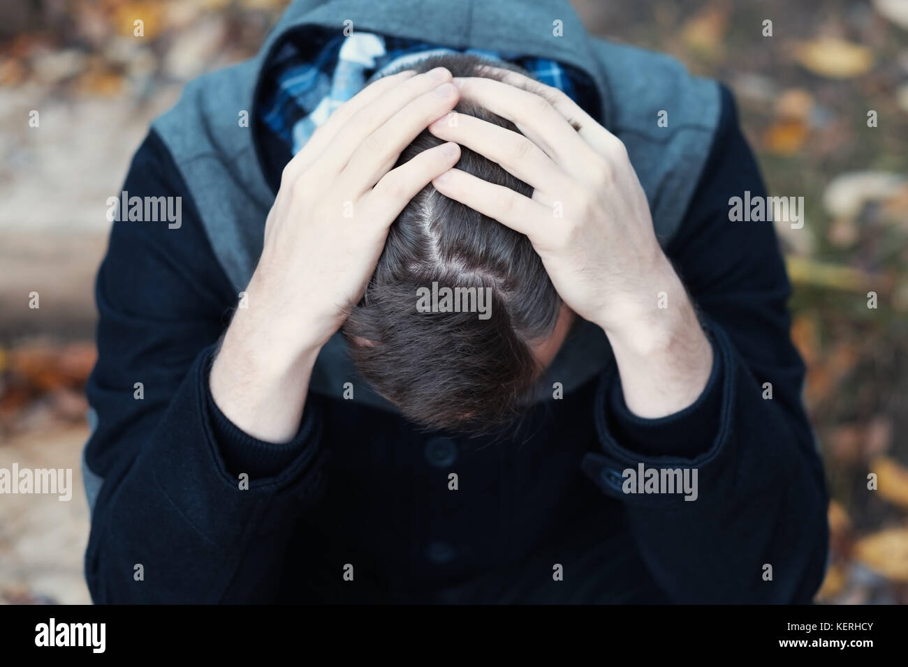 Young man covers his face with his hands in grief or pain. He is ...