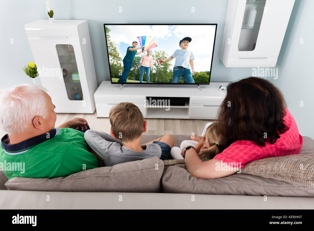 Family With Kids Watching Movie On TV Together At Home Stock Photo