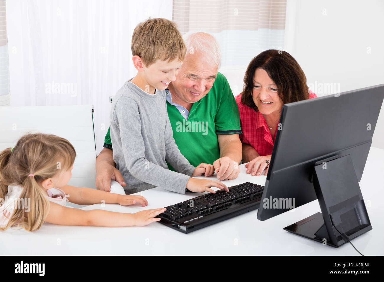 Happy Family With Smiling Kids Using Desktop Computer Together At Home ... image.