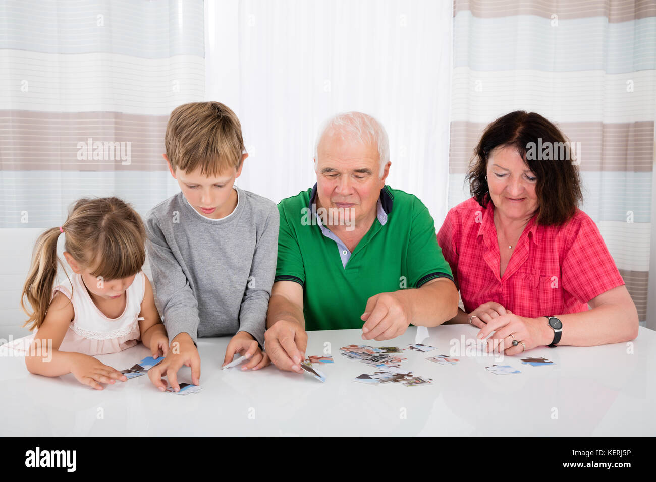Family Holding Jigsaw Puzzle Pieces While Playing Game Stock Photo
