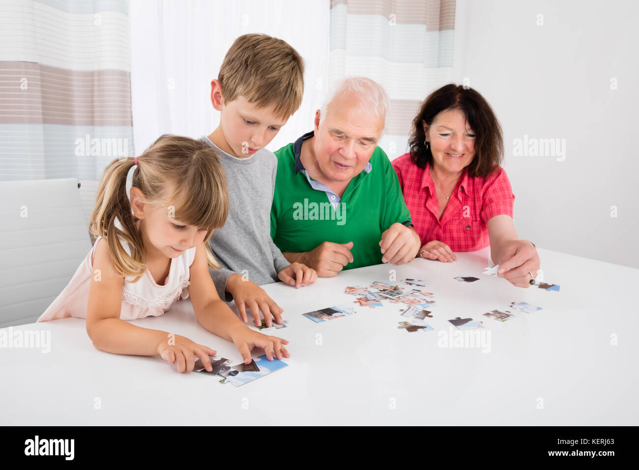 Family Holding Jigsaw Puzzle Pieces While Playing Game Together With Kids Stock Photo