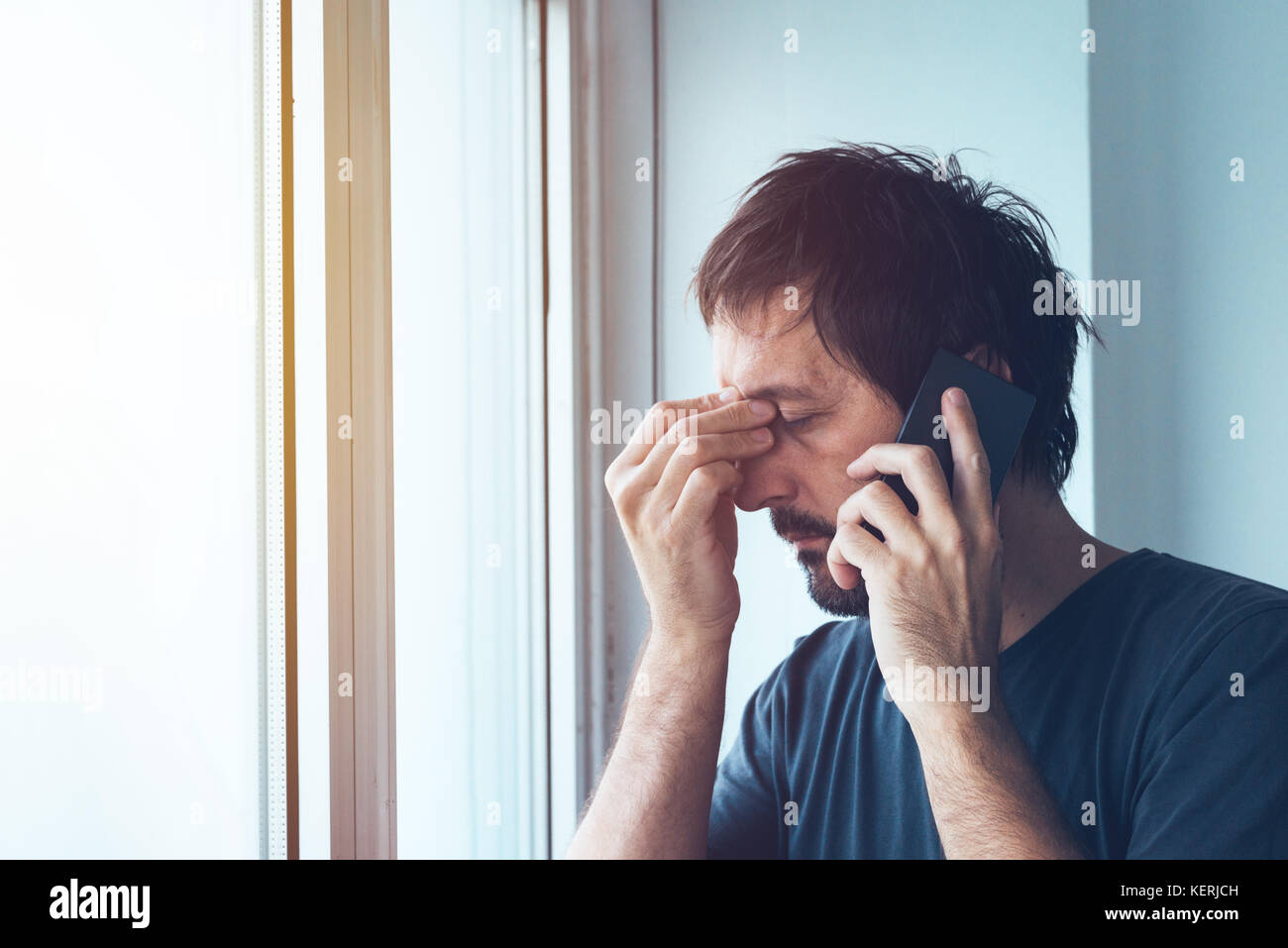 Unpleasant phone call, worried anxious man talking with someone on mobile phone Stock Photo
