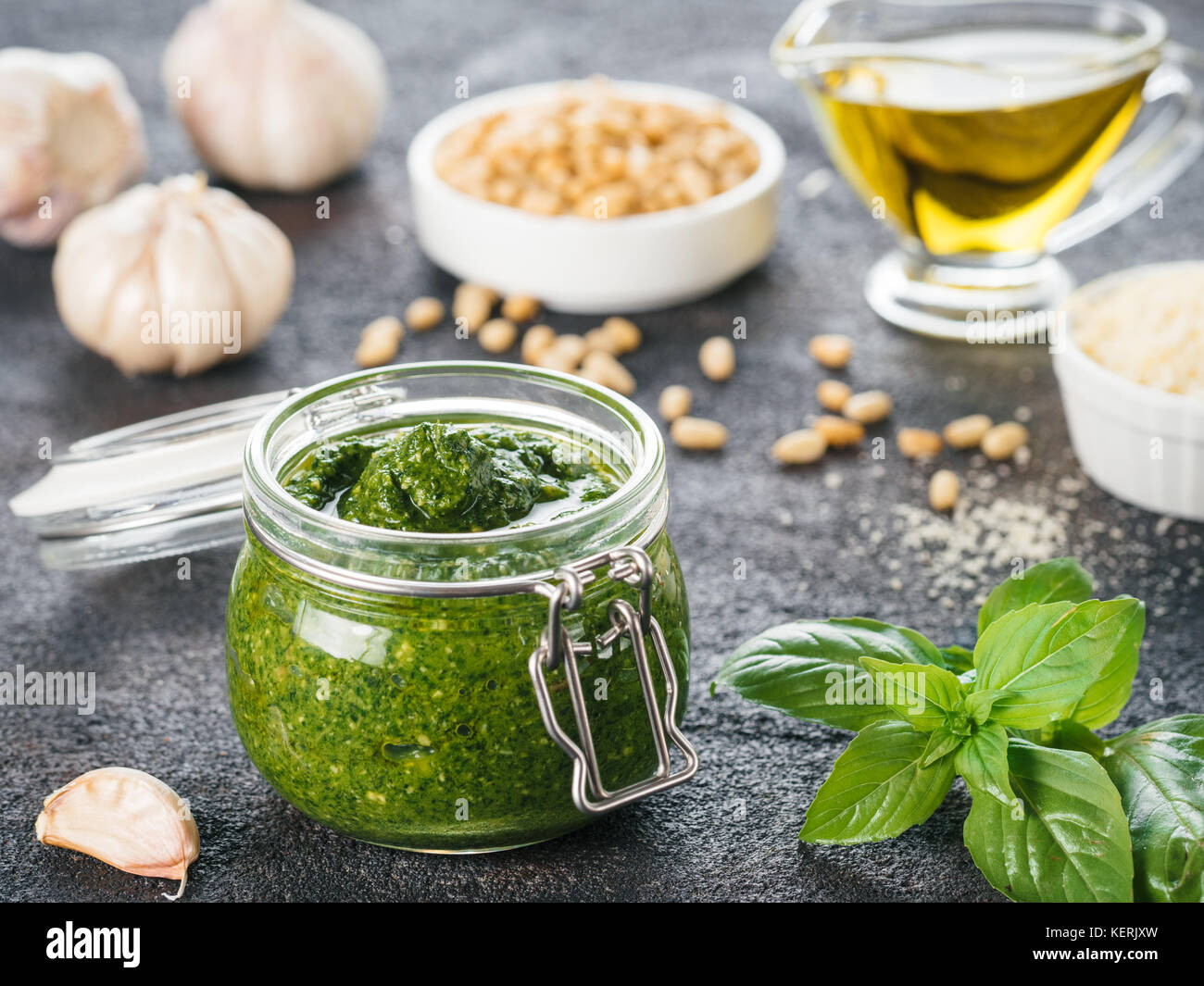 Homemade pesto sauce and ingredients on dark cement background. Close
