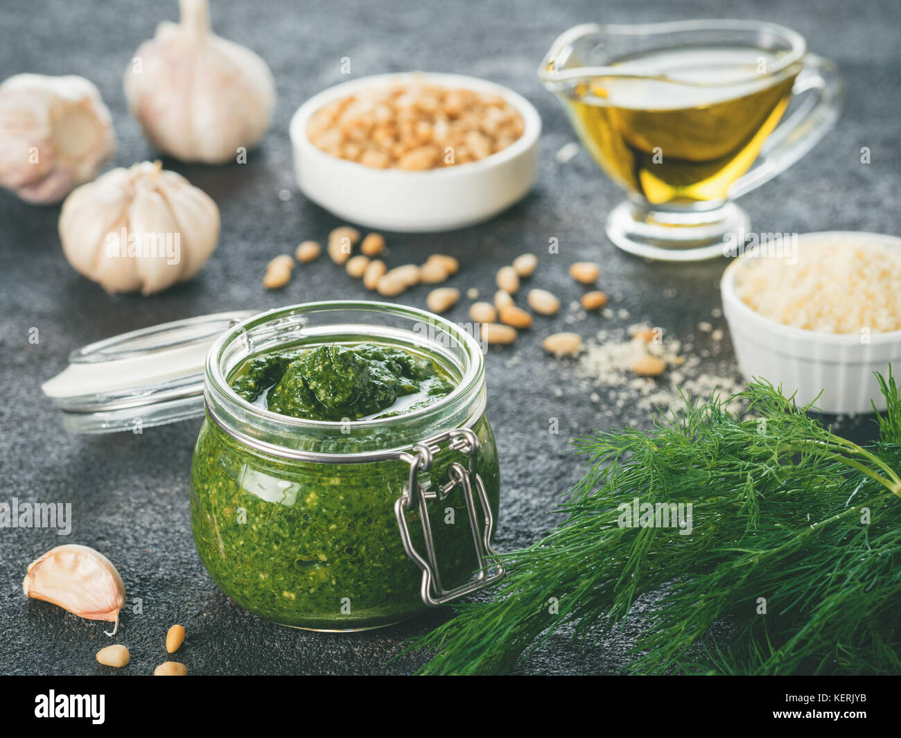 Homemade dill pesto sauce and ingredients on dark cement background