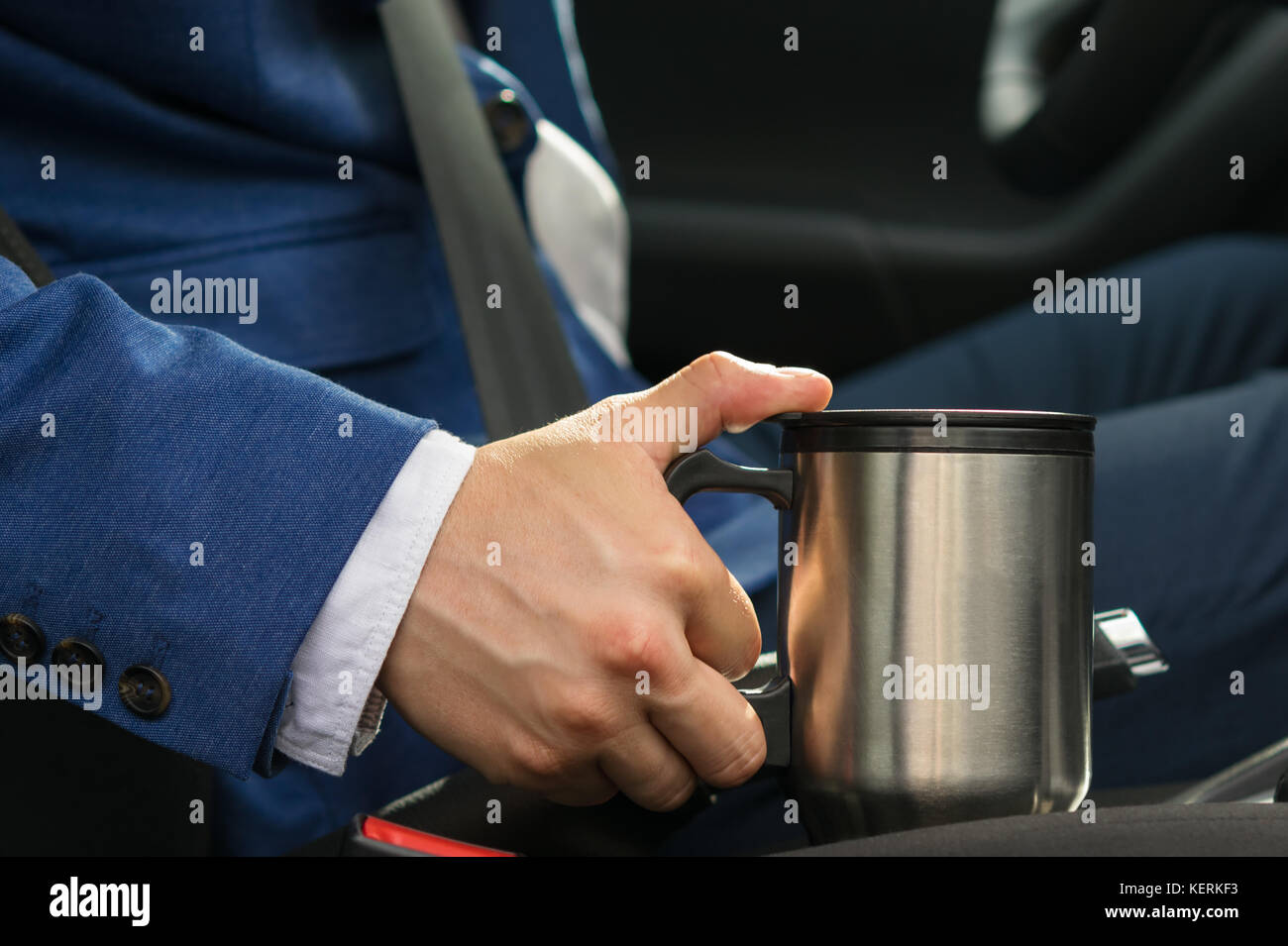 The driver in the car takes a thermos mug with a coffee bar so as not to fall asleep at the wheel Stock Photo