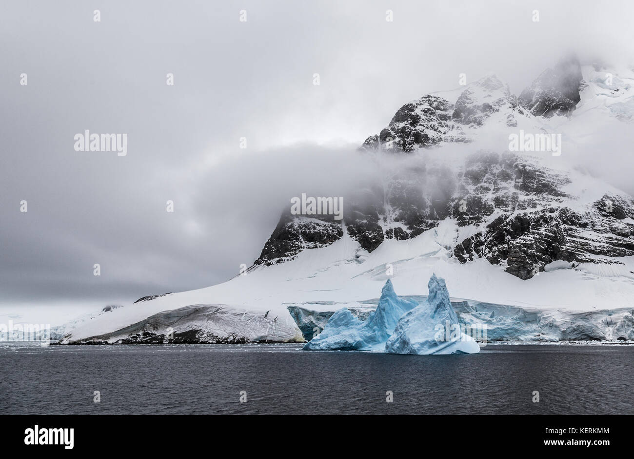Iceberg With Rocks Huge steep stone rock covered with glacier and drifting blue iceberg ...