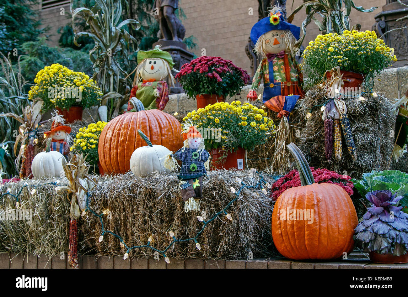 Halloween decoration with pumpkins, cloth scarecrows, hay, lights and pots of flowers. Stock Photo