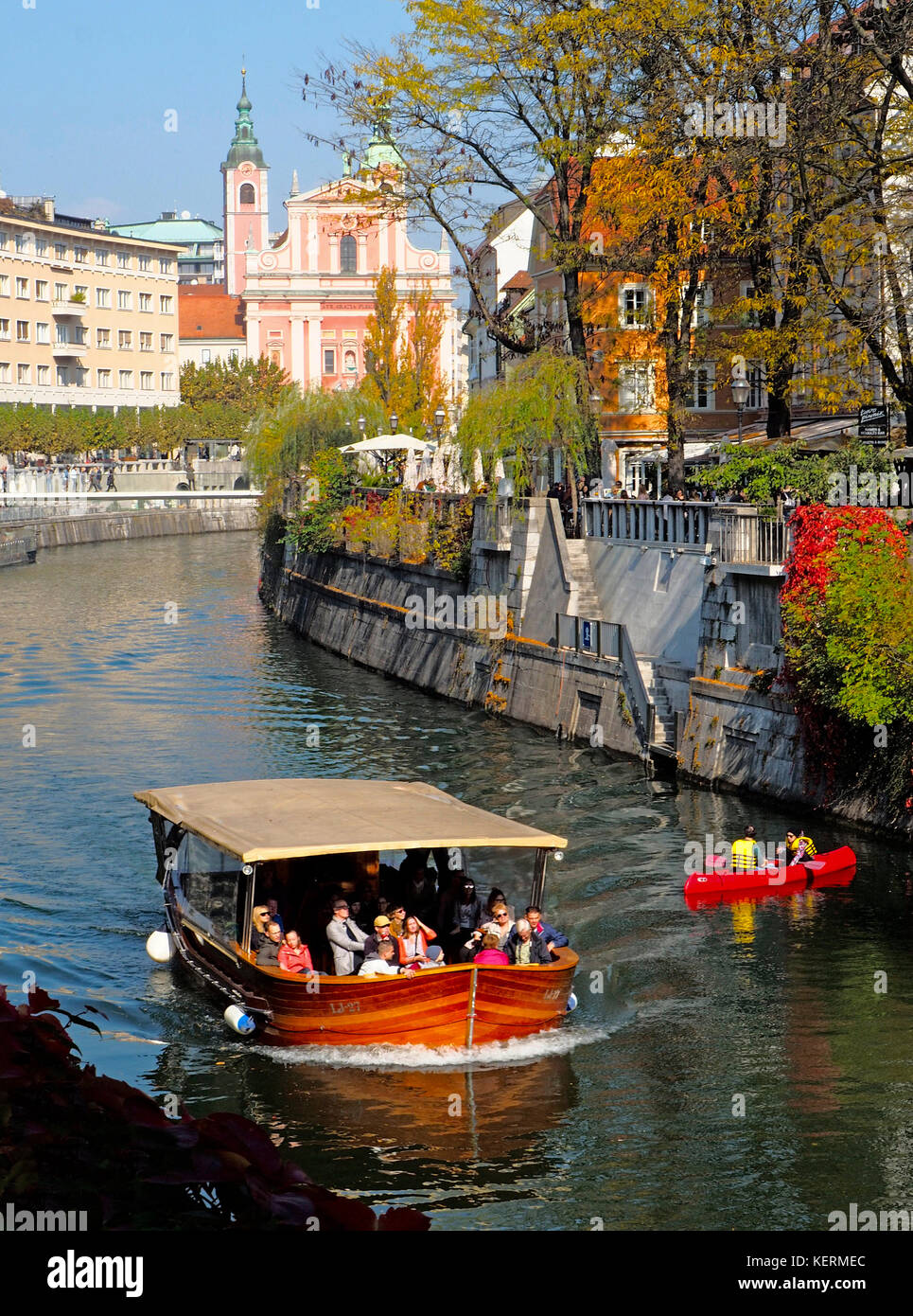 Ljubjlanica River in Old Town Ljubljana, Slovenia, with tourist cruise boat and recreational canoers. Stock Photo