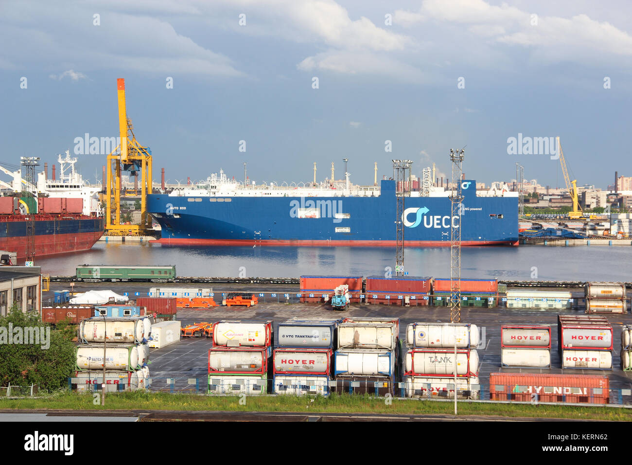 The cargo port. Containers with goods are loaded / unloaded on a commercial vessel using a crane in the harbor of the city. Summer. Business transport Stock Photo