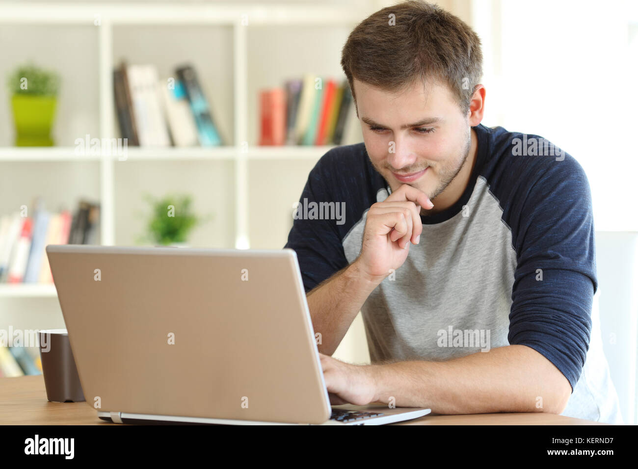 Man finding interesting content on line in a laptop on a table at home Stock Photo