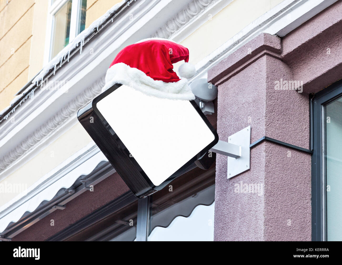 White blank outdoor company signage mockup decorated with red Santa Claus hat during Christmas holidays Stock Photo