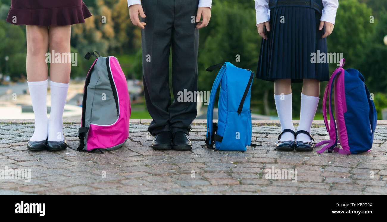 Schoolchildren with backpacks stand in the park ready to go to school, long photo Stock Photo