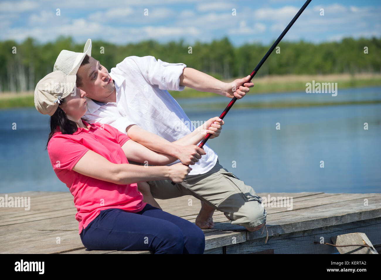 man helps a woman catch a fish from a pier on the river Stock Photo Alamy