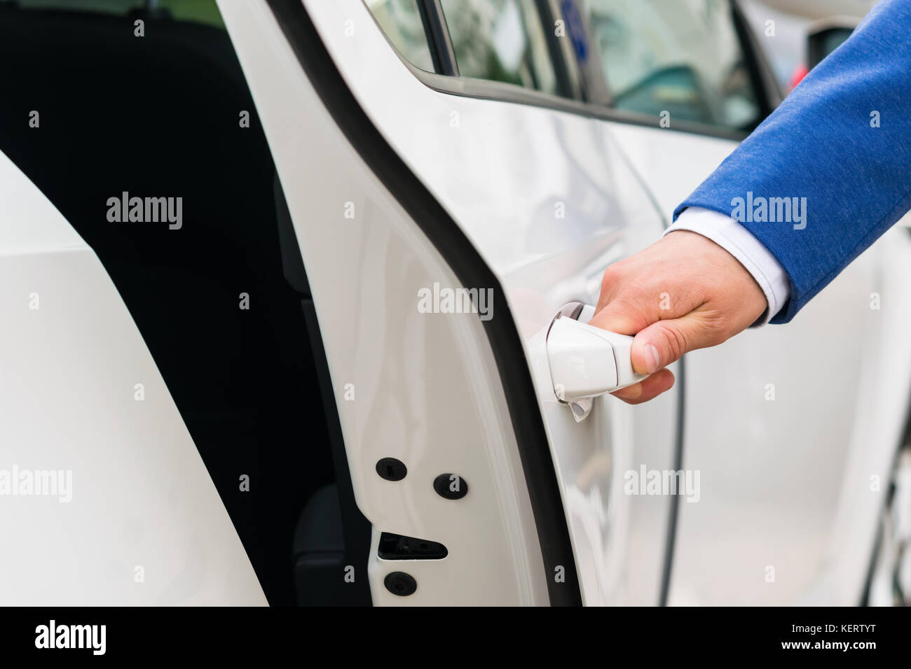 The person's hand holds the handle of the car door and opens the car